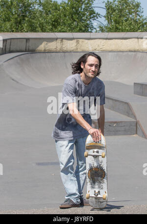 a skateboarder hunk posing with his board Stock Photo