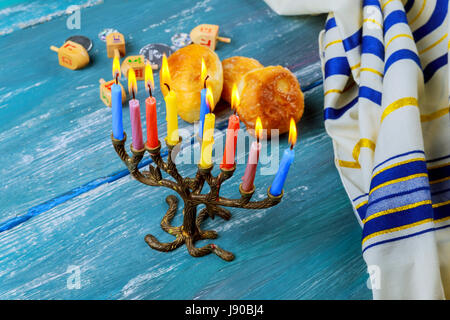 The menorah with candles and sweet donuts are traditional Jewish symbols for the Hanukkah festival. Stock Photo