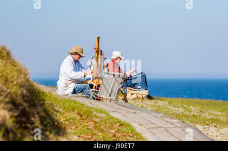 Havang, Sweden - May 18, 2017: Documentary of everyday life at Havang nature reserve. Senior artists painting and drawing by the sea on a sunny evenin Stock Photo