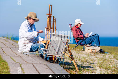 Havang, Sweden - May 18, 2017: Documentary of everyday life at Havang nature reserve. Senior artists painting and drawing by the sea on a sunny evenin Stock Photo