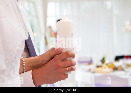 burning candles in the hands of the newlyweds Stock Photo