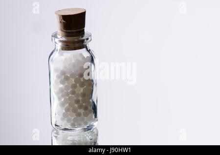 white homepathic globules in a small bottle of glas Stock Photo