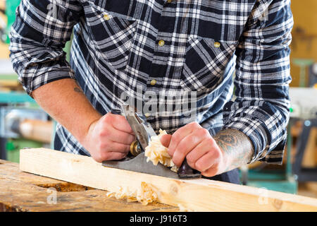 Carpenter work with plane on wood plank Stock Photo