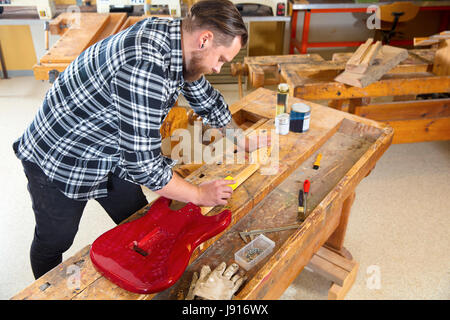 Craftsman sanding a guitar neck in wood at workshop Stock Photo