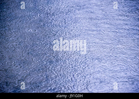 ripples from raindrops falling on pond Stock Photo
