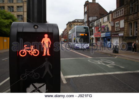 Red light at a pedestrian crossing in Manchester City centre with a city bus approaching Stock Photo