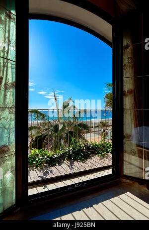 View to the beach and the Mediterranean Sea through the open door. Palm trees and sunny weather. South of Spain Stock Photo