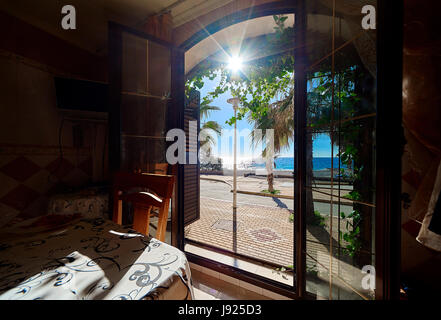 View to the promenade and the Mediterranean Sea through the open door. Palm trees and sunny day. South of Spain Stock Photo