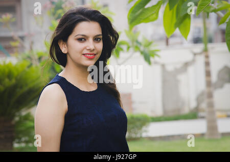 asian girl smiling while posing in a park wearing blue dress Stock Photo