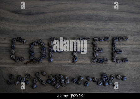 Green coffee beans, scattered on the table and written coffee, brown texture of wood, wood background and coffee beans, black coffee coffee beans Stock Photo