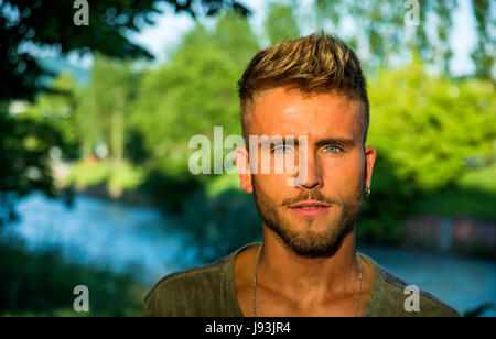 Blondish, blue eyed young man by river Stock Photo