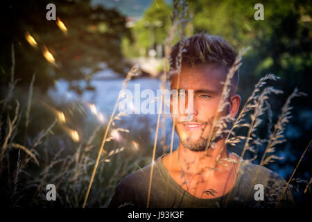 Blondish, blue eyed young man by river Stock Photo