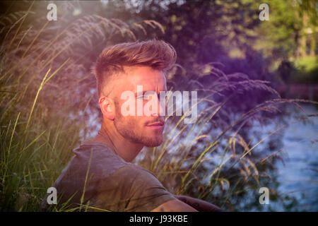 Blondish, blue eyed young man by river Stock Photo