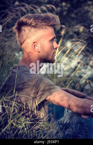 Blondish, blue eyed young man by river Stock Photo