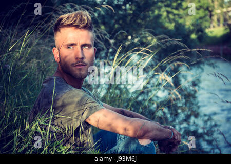 Blondish, blue eyed young man by river Stock Photo