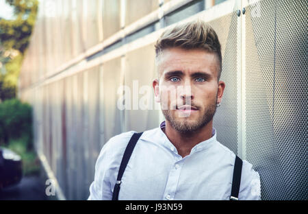 Handsome young man leaning against metal wall Stock Photo