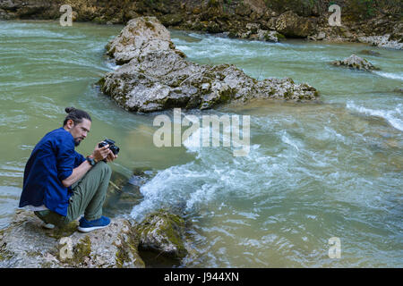 A young guy in a blue shirt shoots a mountain river Stock Photo