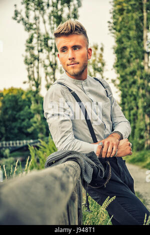 Blondish, blue eyed young man on wood fence Stock Photo