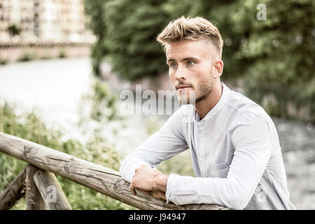 Blondish, blue eyed young man by river Stock Photo