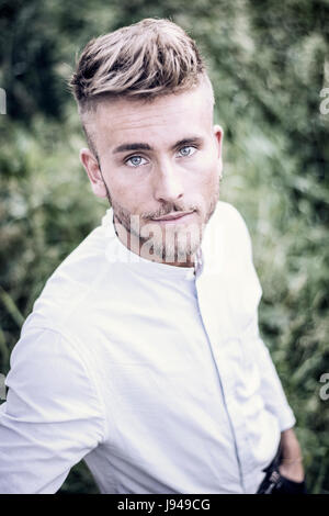 Blondish, blue eyed young man in park Stock Photo