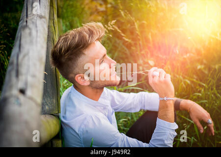Blondish, blue eyed young man on wood fence Stock Photo