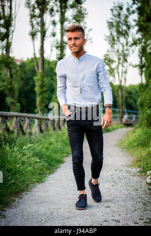 Handsome young man walking in city park Stock Photo