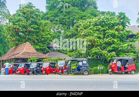 PERADENIYA, SRI LANKA - NOVEMBER 28, 2016: The tuk tuk taxi cabs wait for tourists next to Royal Botanical Garden, on November 28 in Kandy Stock Photo