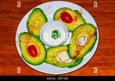 Sliced Avocado gourmet salad with paprika, tomatoes, Feta cheese and Aioli Sauce Stock Photo