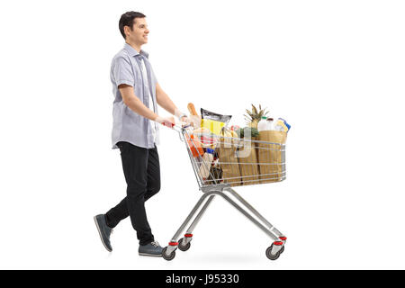 Full length profile shot of a young man pushing a shopping cart filled with groceries isolated on white background Stock Photo