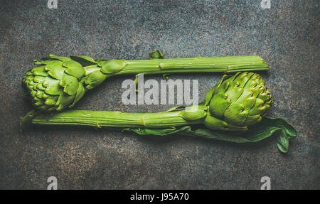 Fresh raw green artichockes over dark brown stone background Stock Photo