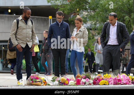 London Bridge. London, UK. 5th June, 2017. Members of public look at the flowers laid by the public on the ground near London Bridge station. At least seven members of the public were killed and dozens injured after three attackers on late 03 June plowed a van into pedestrians and later randomly stabbed people on London Bridge and nearby Borough Market. The three attackers wearing fake suicide vests were shot dead by police who are treating the attack as a 'terrorist incident'. Credit: Dinendra Haria/Alamy Live News Stock Photo