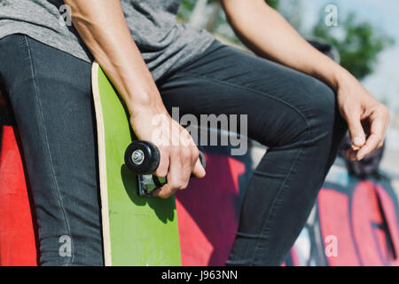 closeup of a young caucasian man with a skate board in his hand in an outdoors skate park Stock Photo