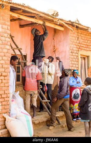 Men using home made ladder to hang scales to weigh sacks of maize for sale to a trader in the rural village of Chiphazi near Dedza Malawi, Africa Stock Photo