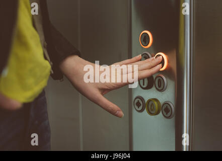 Woman pressing button inside elevator. Stock Photo