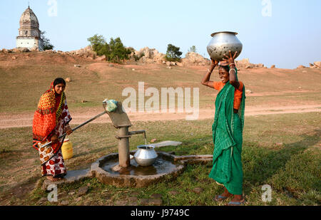 Rural tribal women are carrying water pipkin for collecting drinking water  in a remote village of  India. Stock Photo