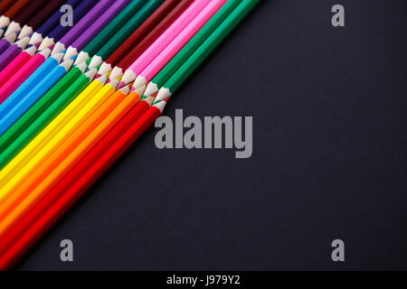 colored pencils on dark background lying in opposite corners Stock Photo
