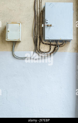 Electrical switchboard on the wall. Wiring to the electrical panel on the wall. Detail of the cityscape. Grey wall Stock Photo