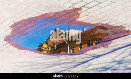 Reflection of the roof of the building in the water on the pavement. Cityscape abstract background Stock Photo
