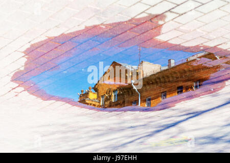Reflection of the roof of the building in the water on the pavement. Cityscape abstract background Stock Photo