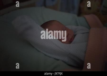 Night portrait of sleeping little baby boy with raised hand Stock Photo