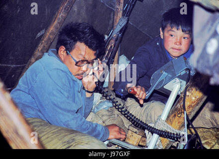 Nomadic Chukchi reindeer herders' yurt encampment on the Chukchi or Chukotka Peninsula, in the Russian Far East. Father is talking on shortwave radio  Stock Photo