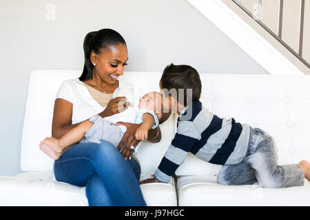 Mother with two sons (2-5 months, 2-3) on sofa Stock Photo