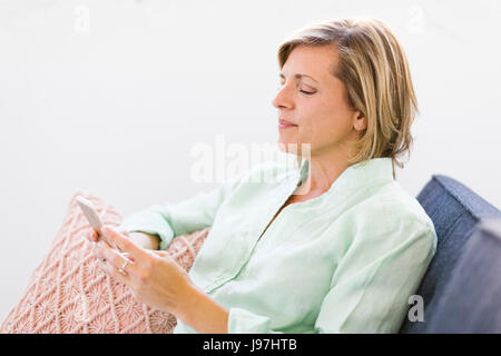 Woman using smart phone on sofa Stock Photo