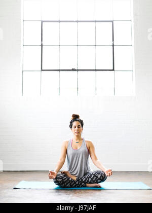 Woman meditating on exercise mat Stock Photo