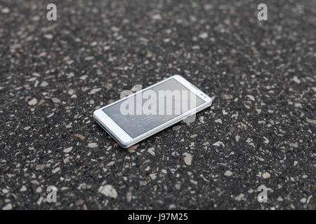 Phone with broken screen lying on the street Stock Photo