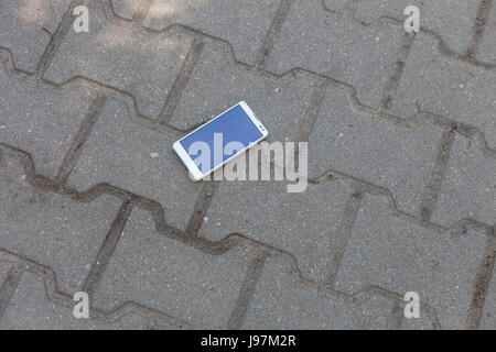 Phone with broken screen lying on the pavement Stock Photo