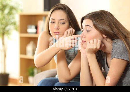 Bored friends trying to have fun sitting on a couch in the living room at home Stock Photo