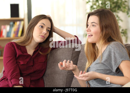 Bored girl listening to her friend having a conversation sitting on a couch in the living room at home Stock Photo