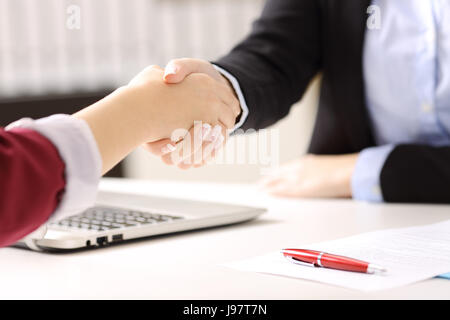 Close up of two businesswomen hands handshaking after closing a deal and signing contract in a desk with an office background Stock Photo