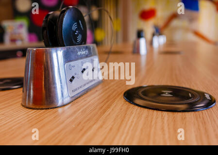 QI wireless chargers built into a table at a McDonald's restaurant, with wireless receiver adapters for devices without wireless capability Stock Photo